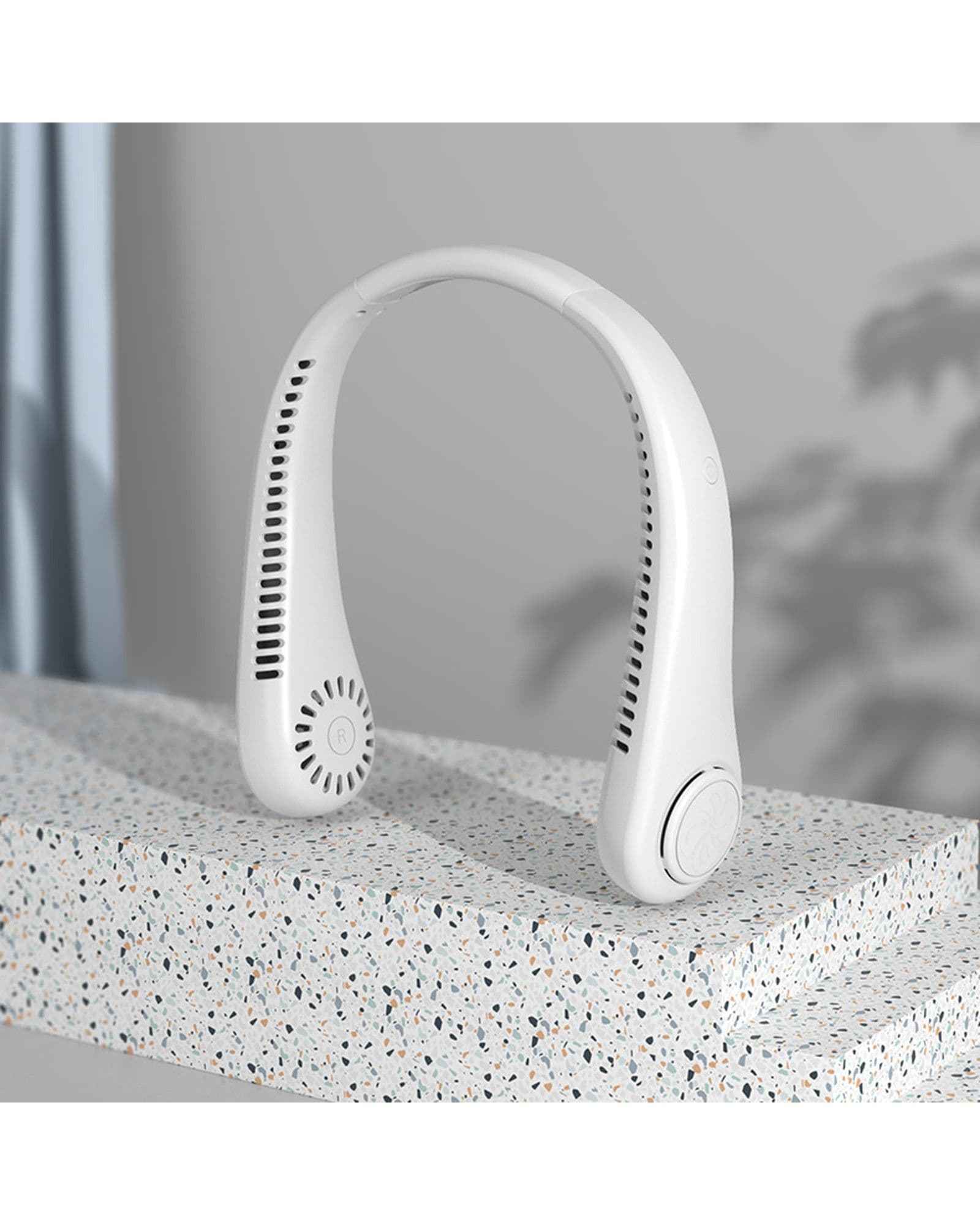 Airbro FNE-100 white wearable neck fan displayed on a speckled stone surface in a minimalist indoor setting.