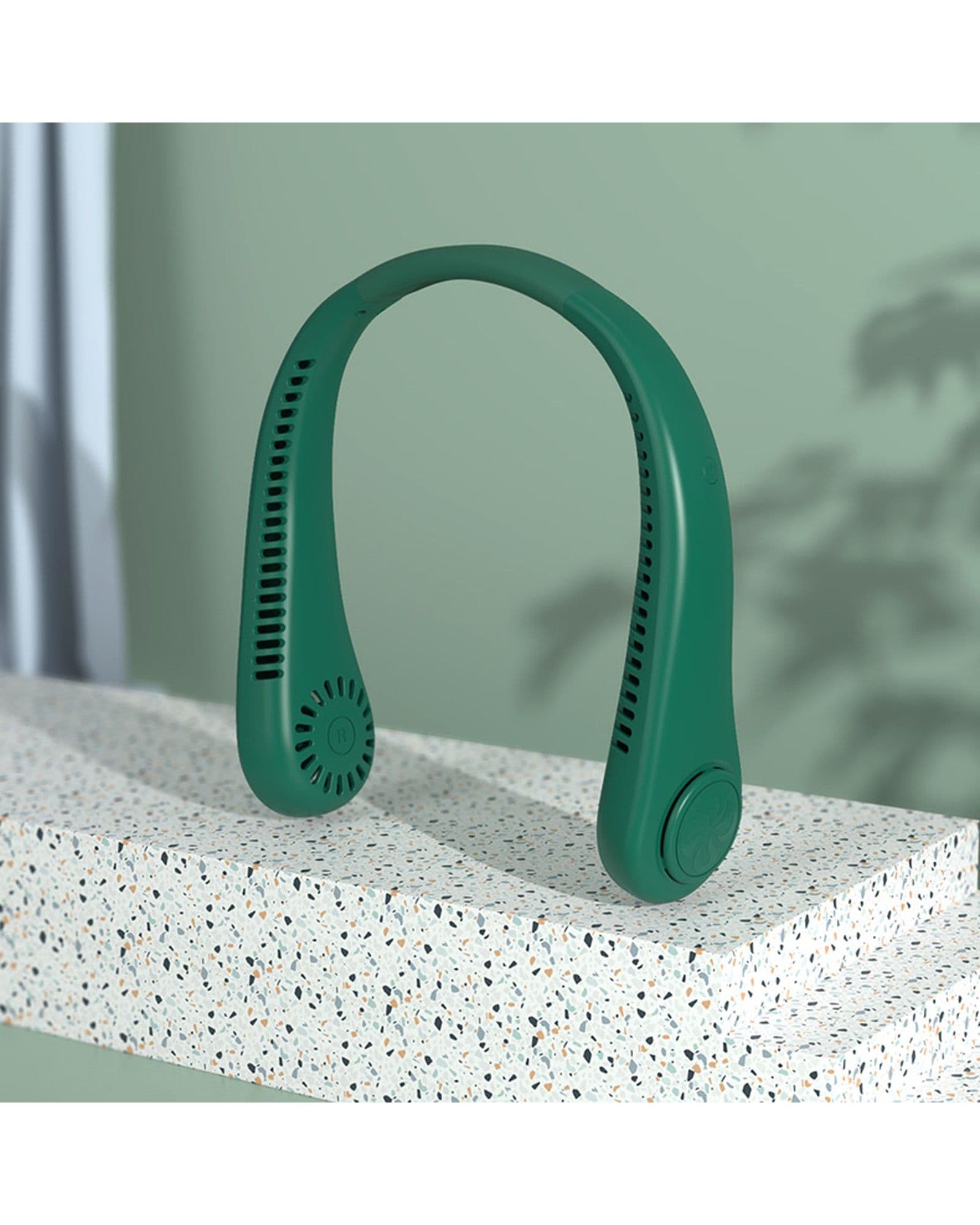 A dark green Airbro FNE-100 neck fan displayed on a speckled stone platform against a soft green background.