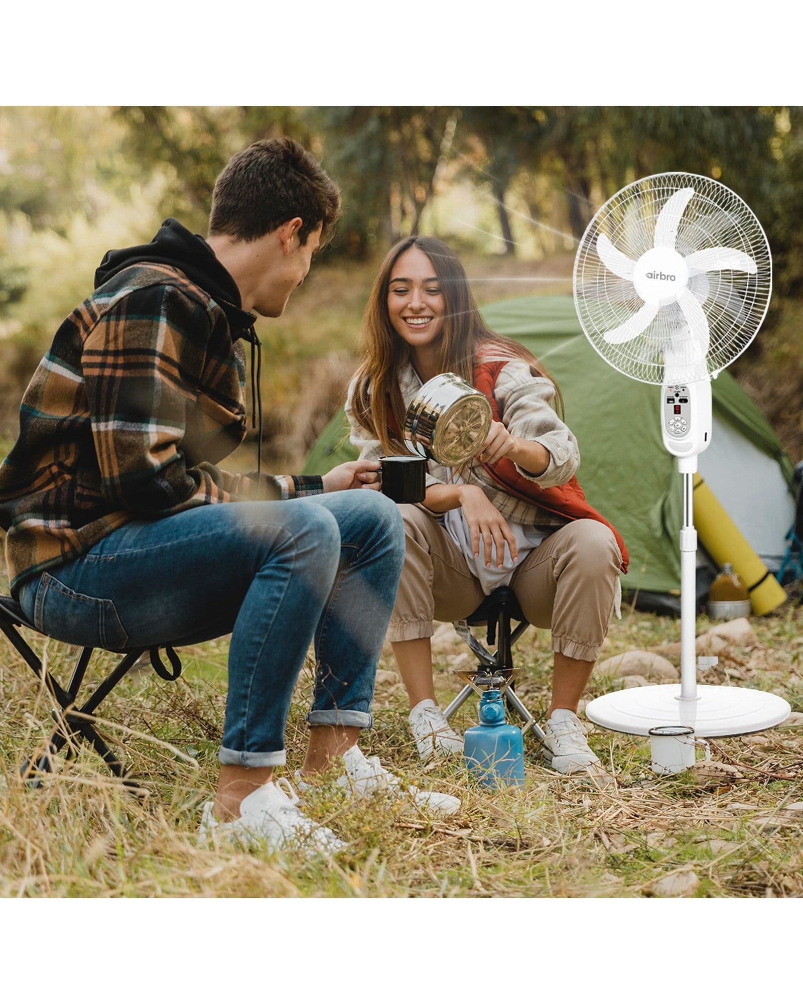 A couple camping outdoors with an Airbro FSA-180 pedestal fan standing next to them.
